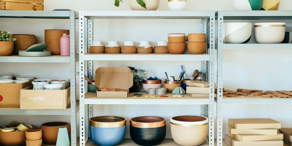 Metal garage shelves neatly arranged with pottery, tools, and storage boxes, showcasing practical and creative garage shelving ideas for organization and space efficiency