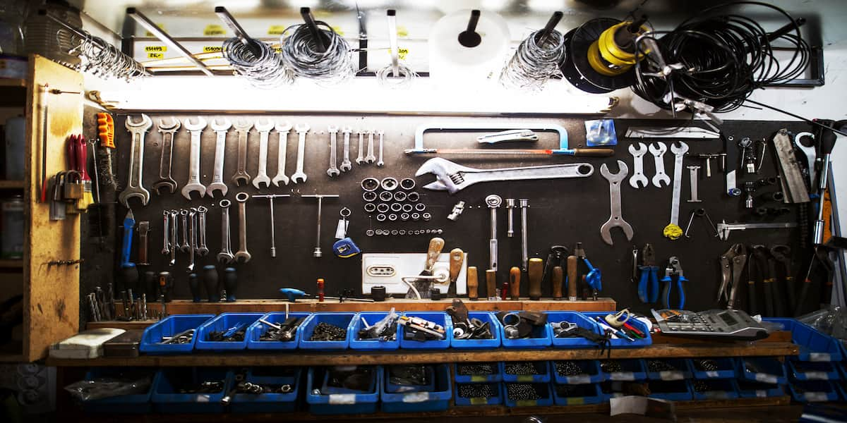 Well-organized garage workspace featuring a wall-mounted tool rack with neatly arranged wrenches and tools, along with labeled bins for small parts, exemplifying effective garage tool organization.