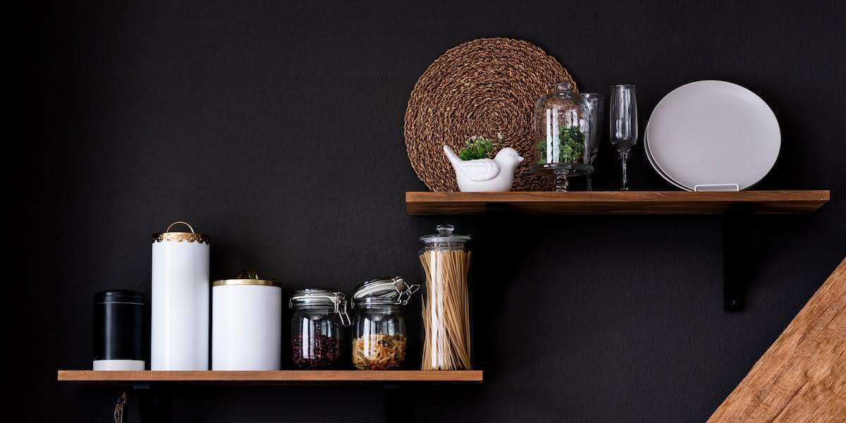 Stylish kitchen shelves with jars, plates, and decor on a dark wall showcasing practical kitchen shelving ideas for organized and modern storage