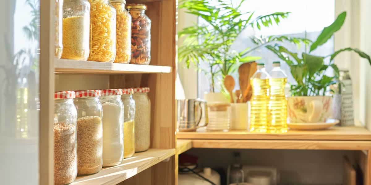 Shelves with organized pantry items in glass jars and bottles, highlighting the benefits of a pantry clean out for a tidy and functional kitchen.