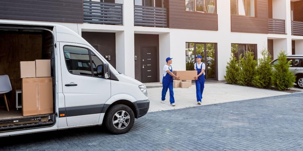 Movers unloading boxes from a van using professional packing services at a modern residential home